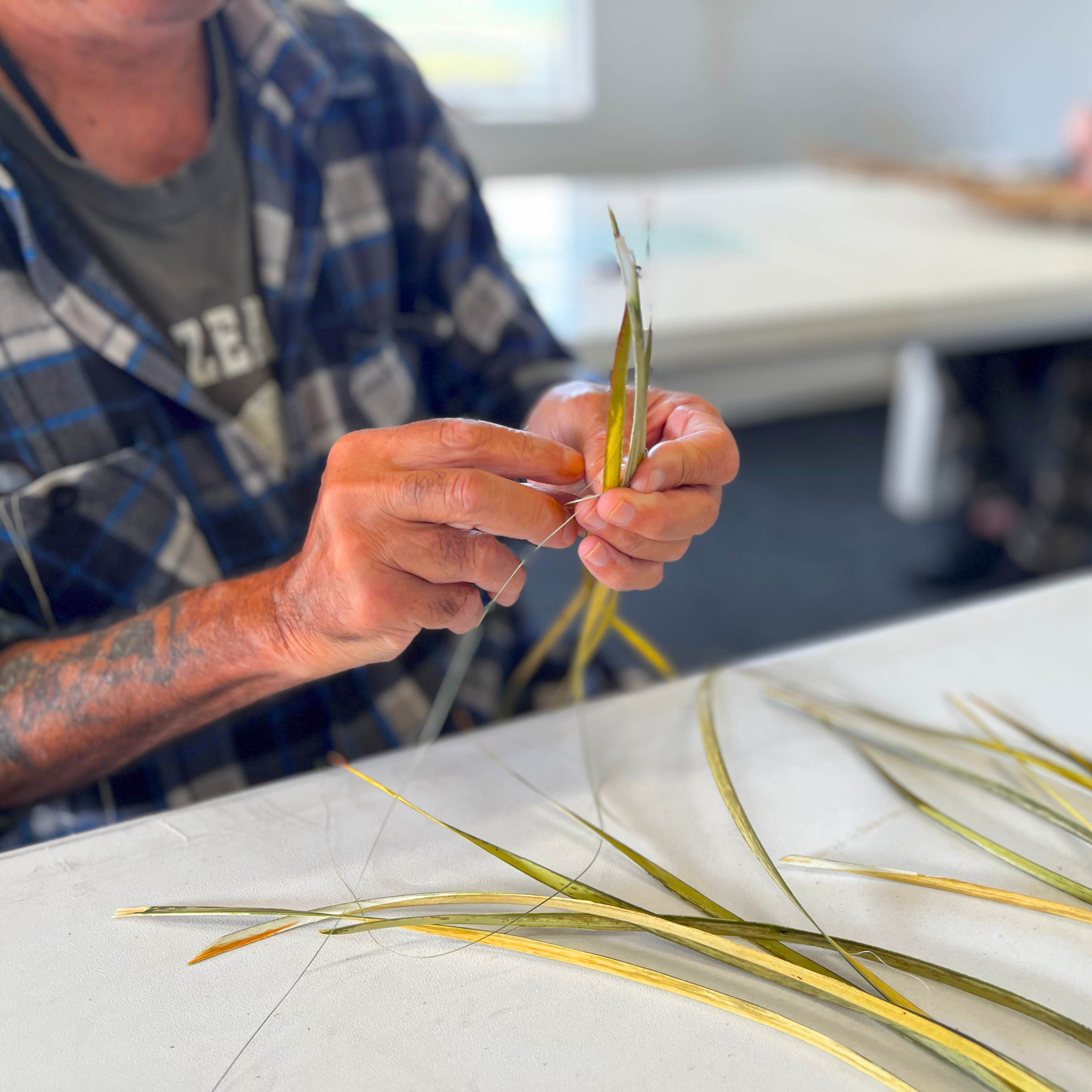 About us pictured: A male weaving with flax.